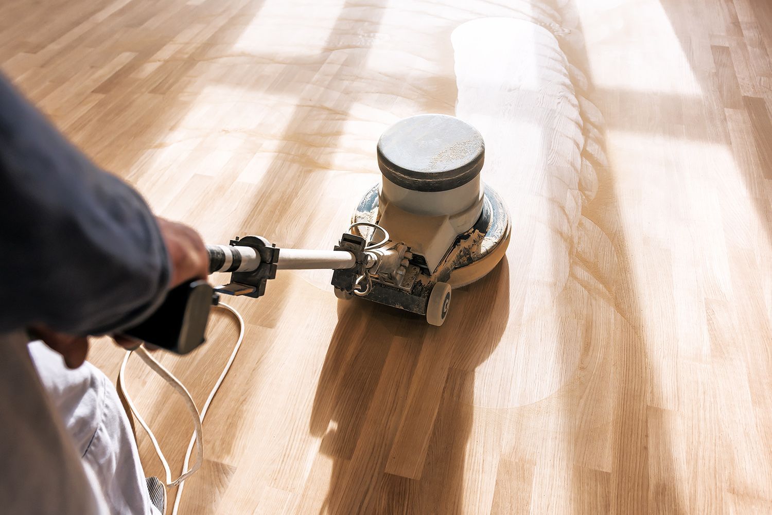 A person is using a machine to polish a wooden floor.
