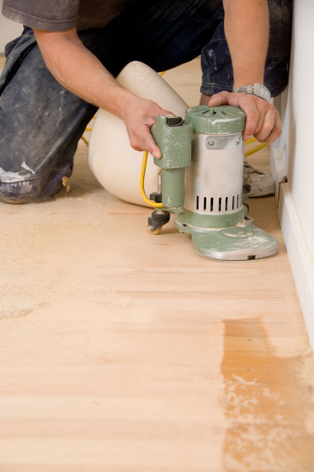 A man is sanding a wooden floor with a machine.