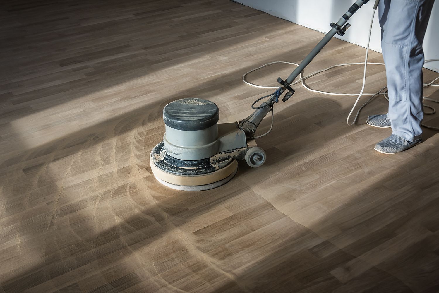 A person is using a machine to polish a wooden floor.