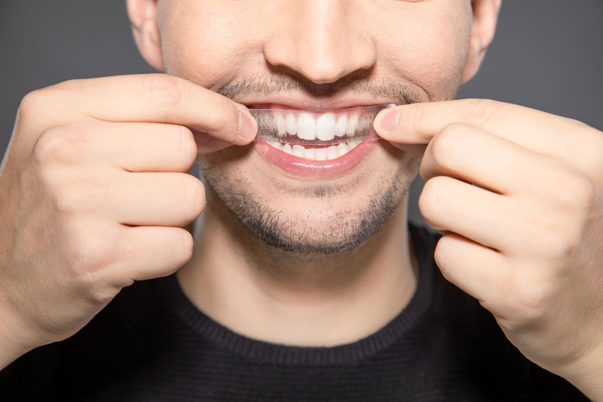 young man with a teeth whitening strip on his teeth