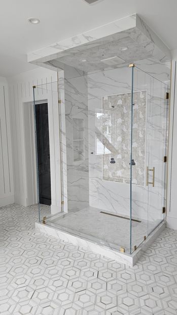 A bathroom with a walk in shower with a glass door.