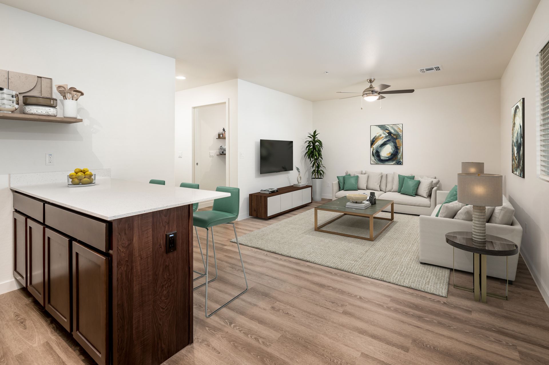 Open-concept living area with kitchen island, sofas, TV, and light wood flooring.