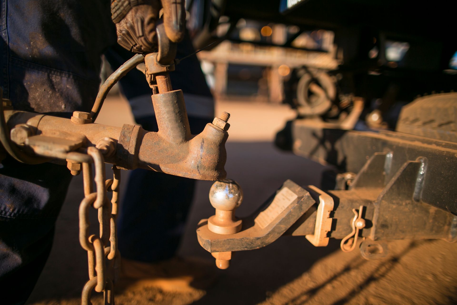 Person Connecting a Rusty Trailer Hitch to a Ball Hitch on a Vehicle — Penfold Towing in Tiaro, QLD