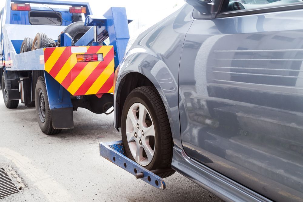 Tow Truck Lifting a Gray Car’s Front Wheel — Penfold Towing in Urangan, QLD