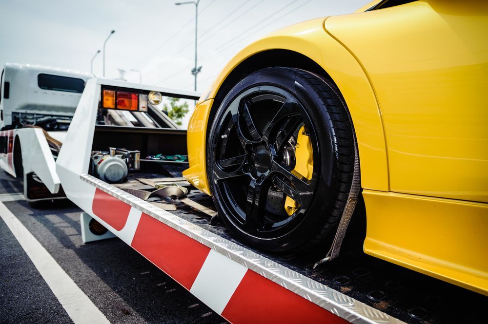 A Yellow Sports Car Being Towed on a Flatbed Tow Truck — Penfold Towing in Urangan, QLD