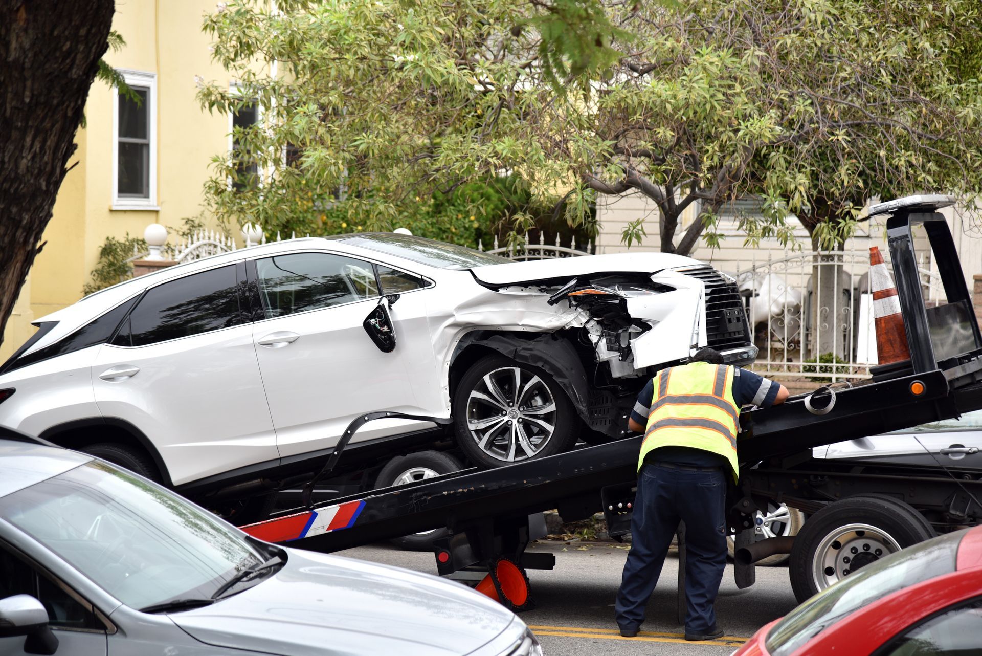 A Damaged White Car is Loaded Onto a Tow Truck on a City Street — Penfold Towing in Urangan, QLD