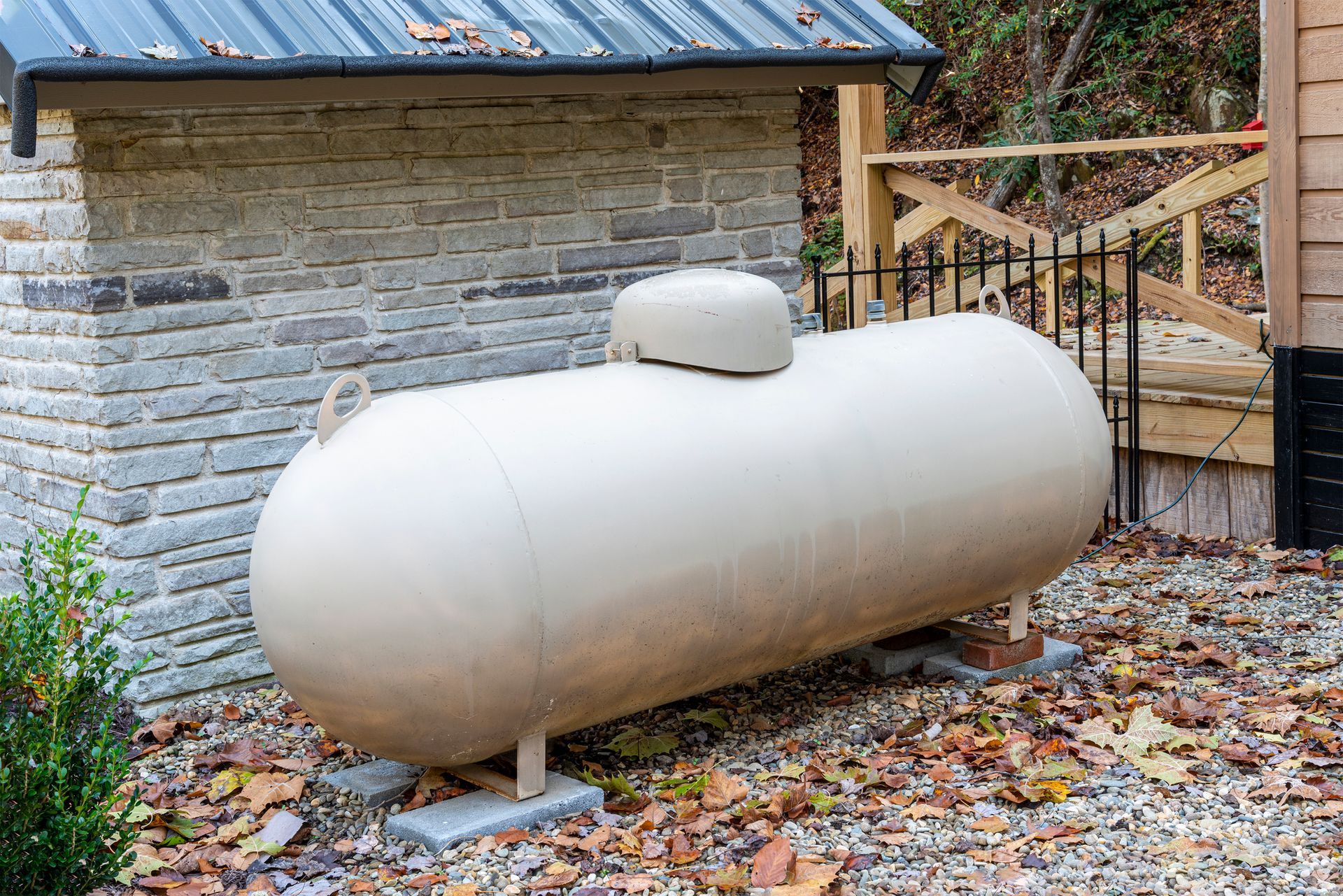 A large white propane tank is sitting in front of a brick building.