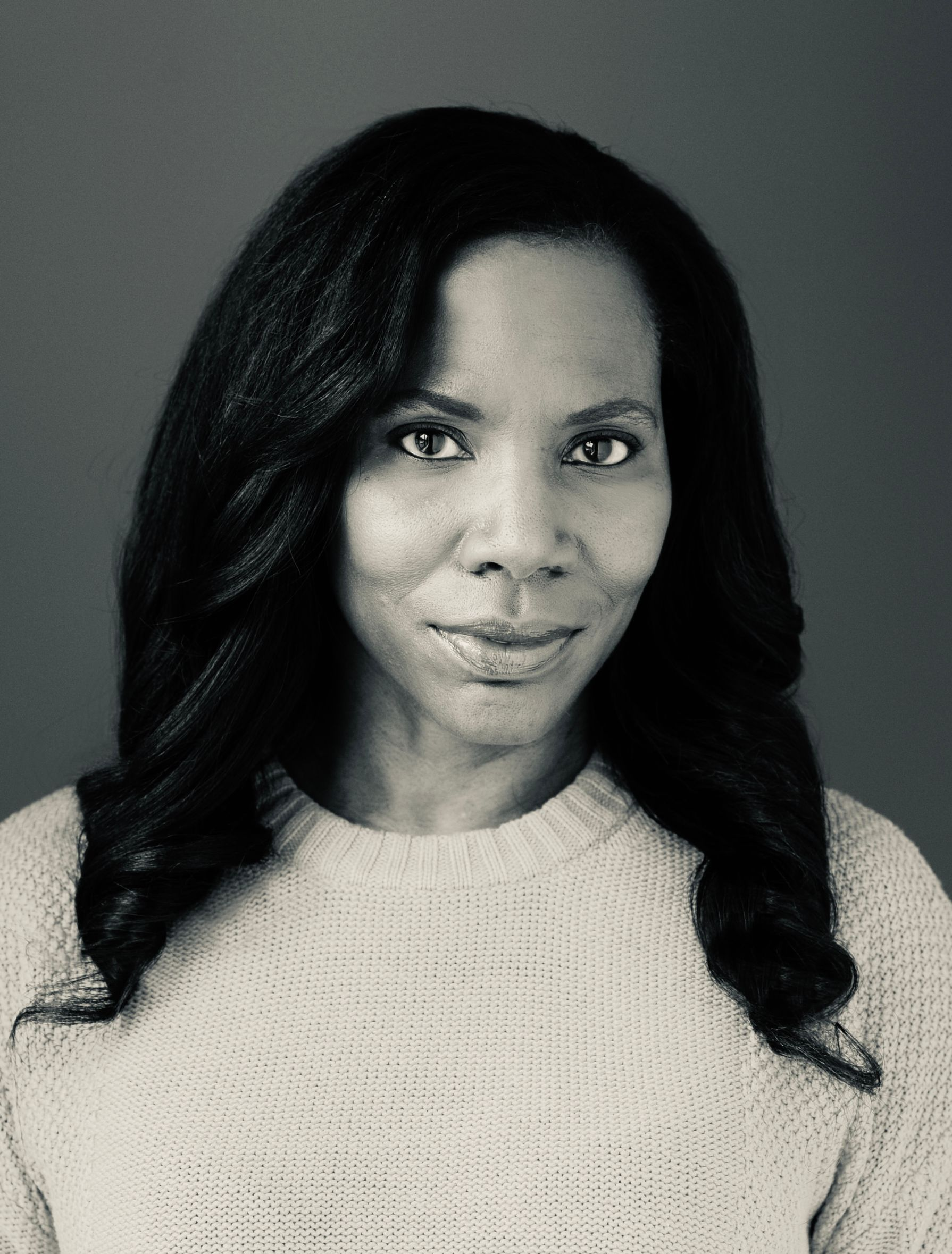 A dining room with a table and chairs and a wooden staircase.