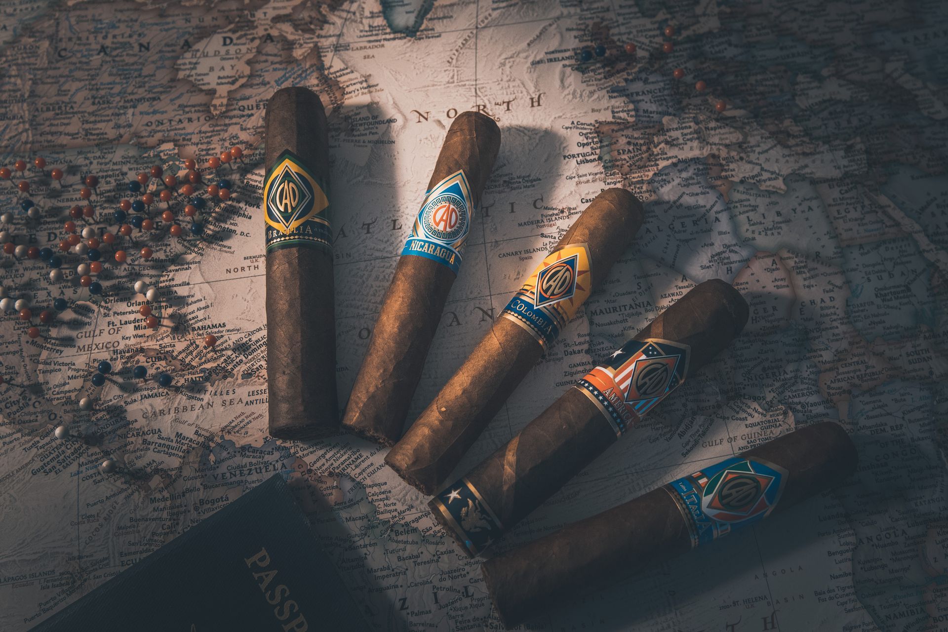 Five cigars with decorative bands on a map and a passport.