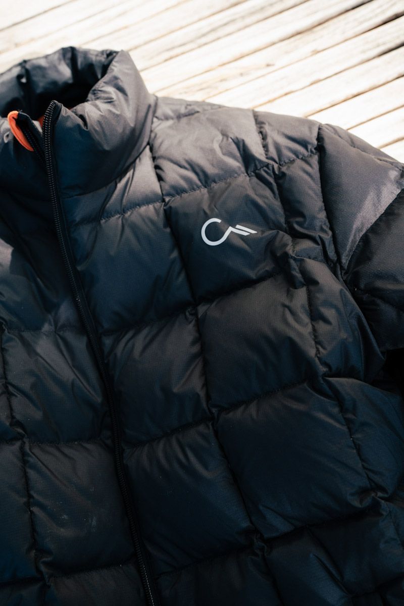 Black quilted puffer jacket with a small white logo on a textured surface.