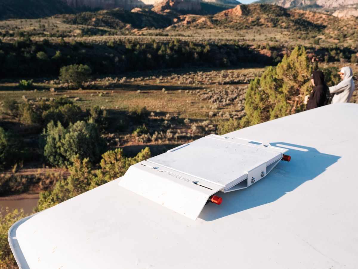 White Starlink on a rooftop overlooking a green valley and distant red cliffs.