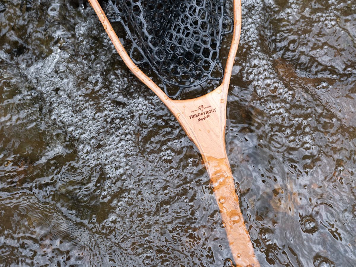 Wooden fishing net in water, with mesh.