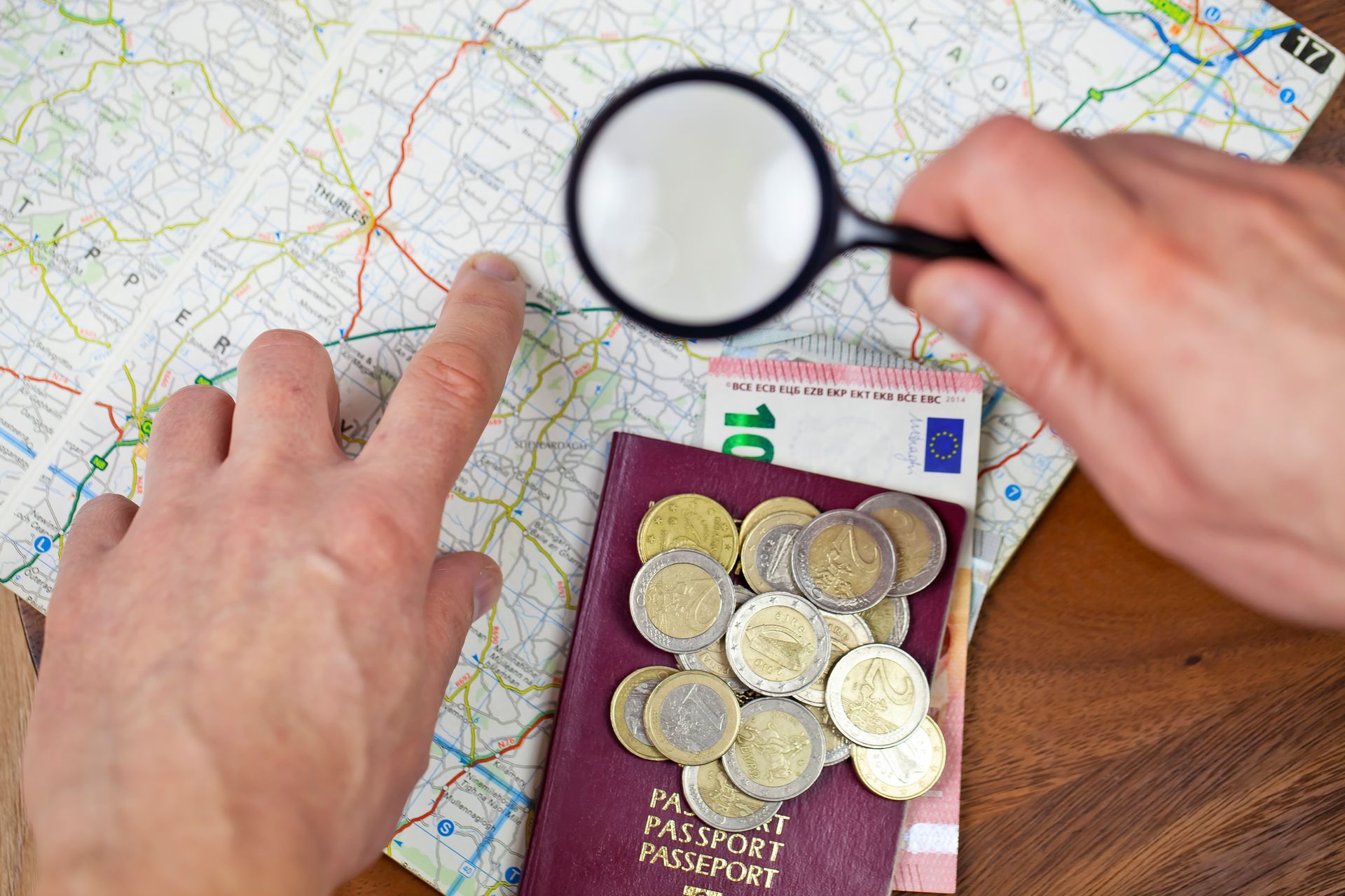 A person is looking at a map with a magnifying glass.