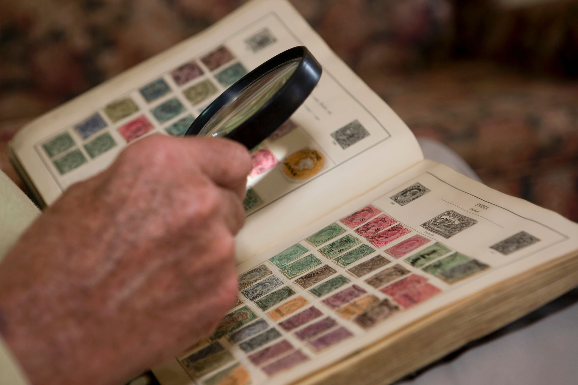 A person is looking at stamps with a magnifying glass