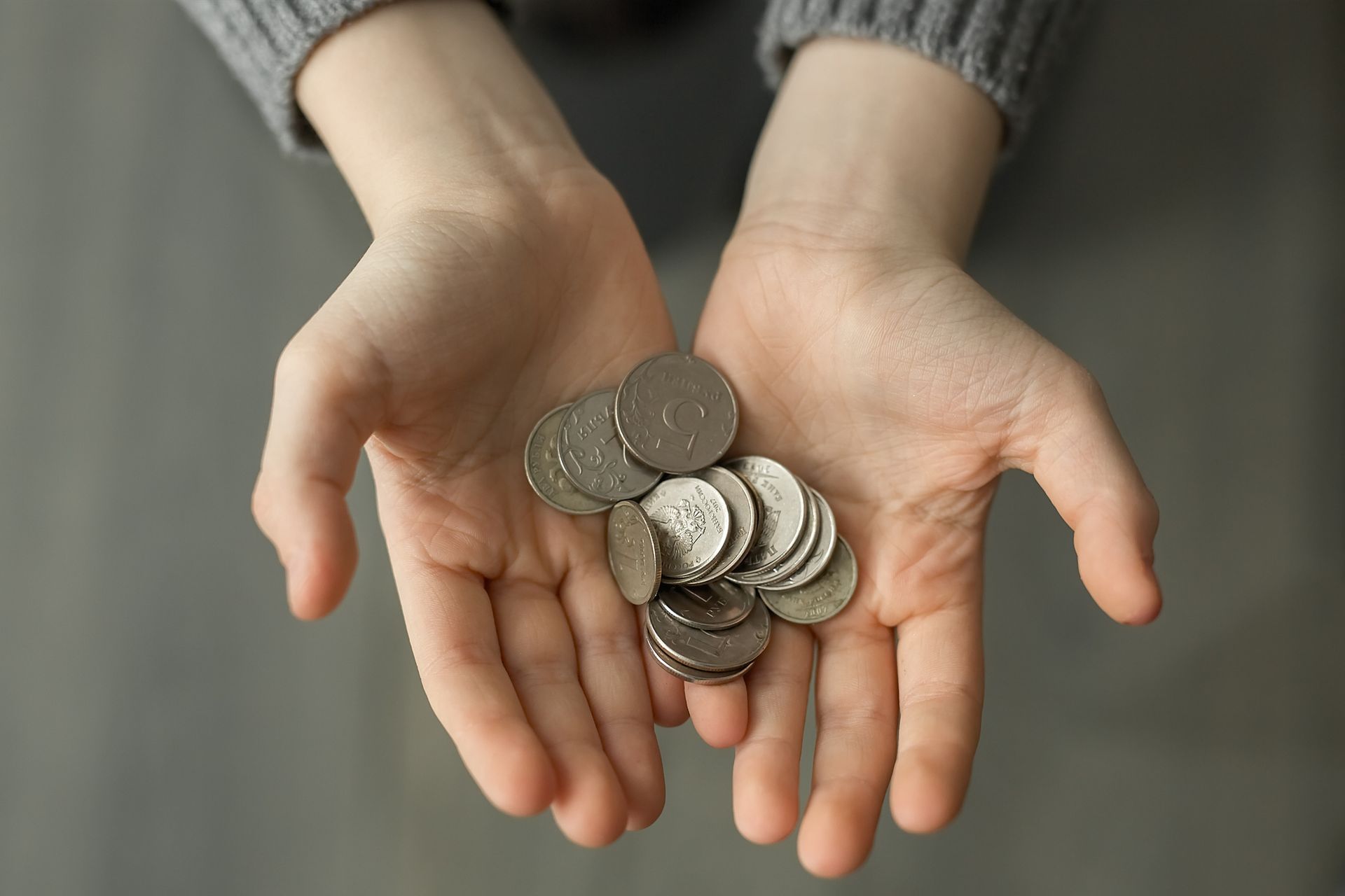 A couple of hands are holding coins.