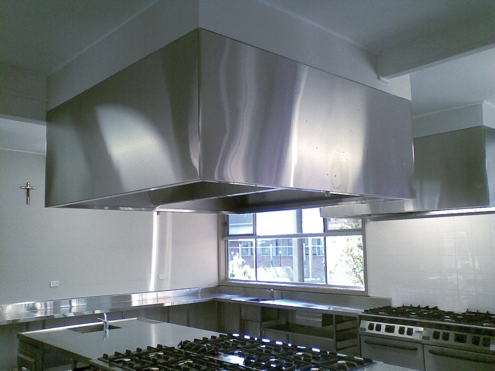 A kitchen with stainless steel appliances and a cross on the wall