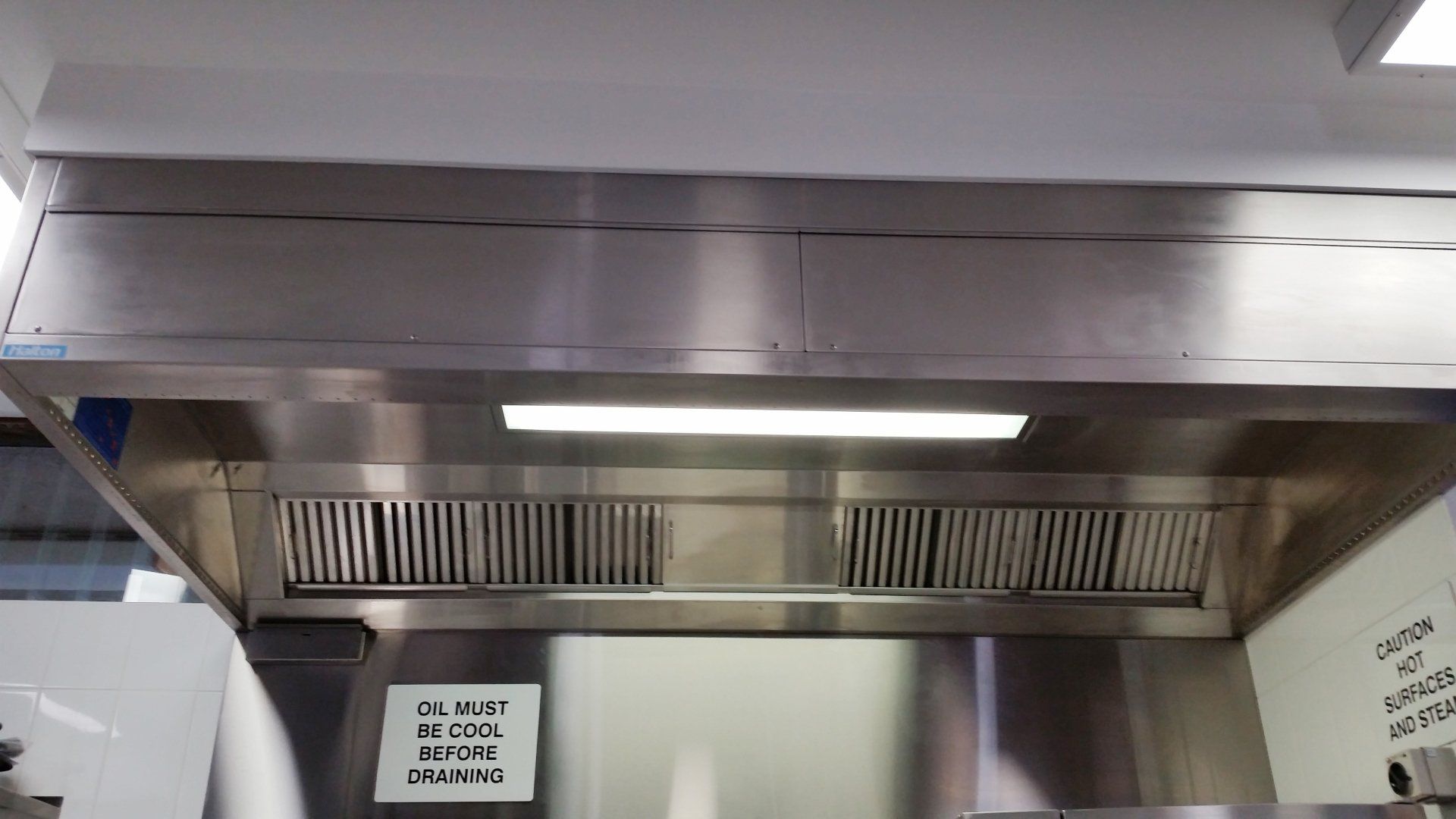 A stainless steel hood with a sign on it that says 
