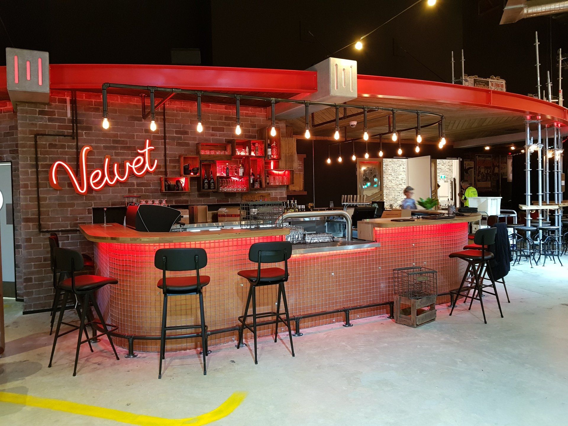 A bar with stools and a neon sign that says velvet.