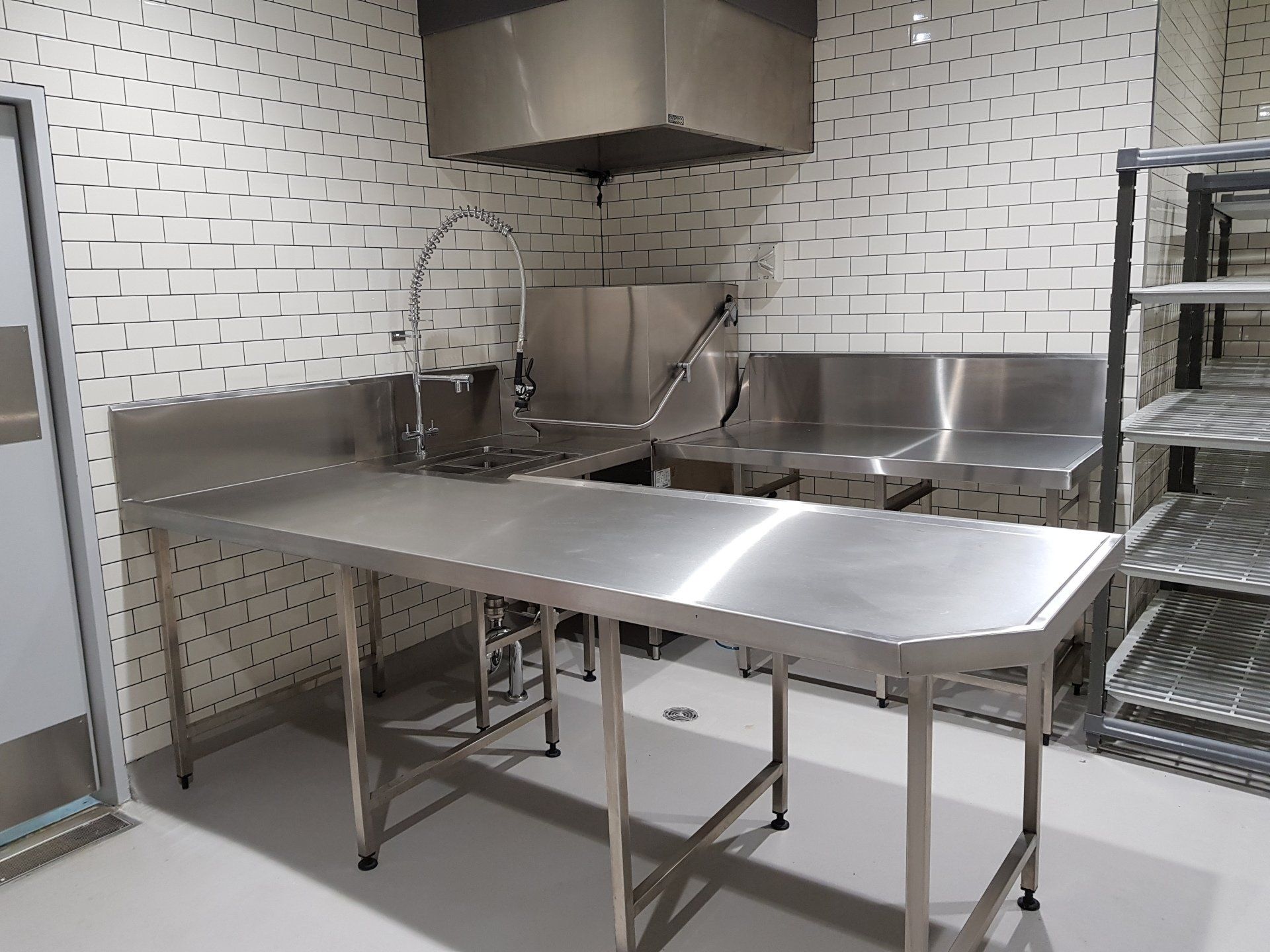A kitchen with a stainless steel table and sinks
