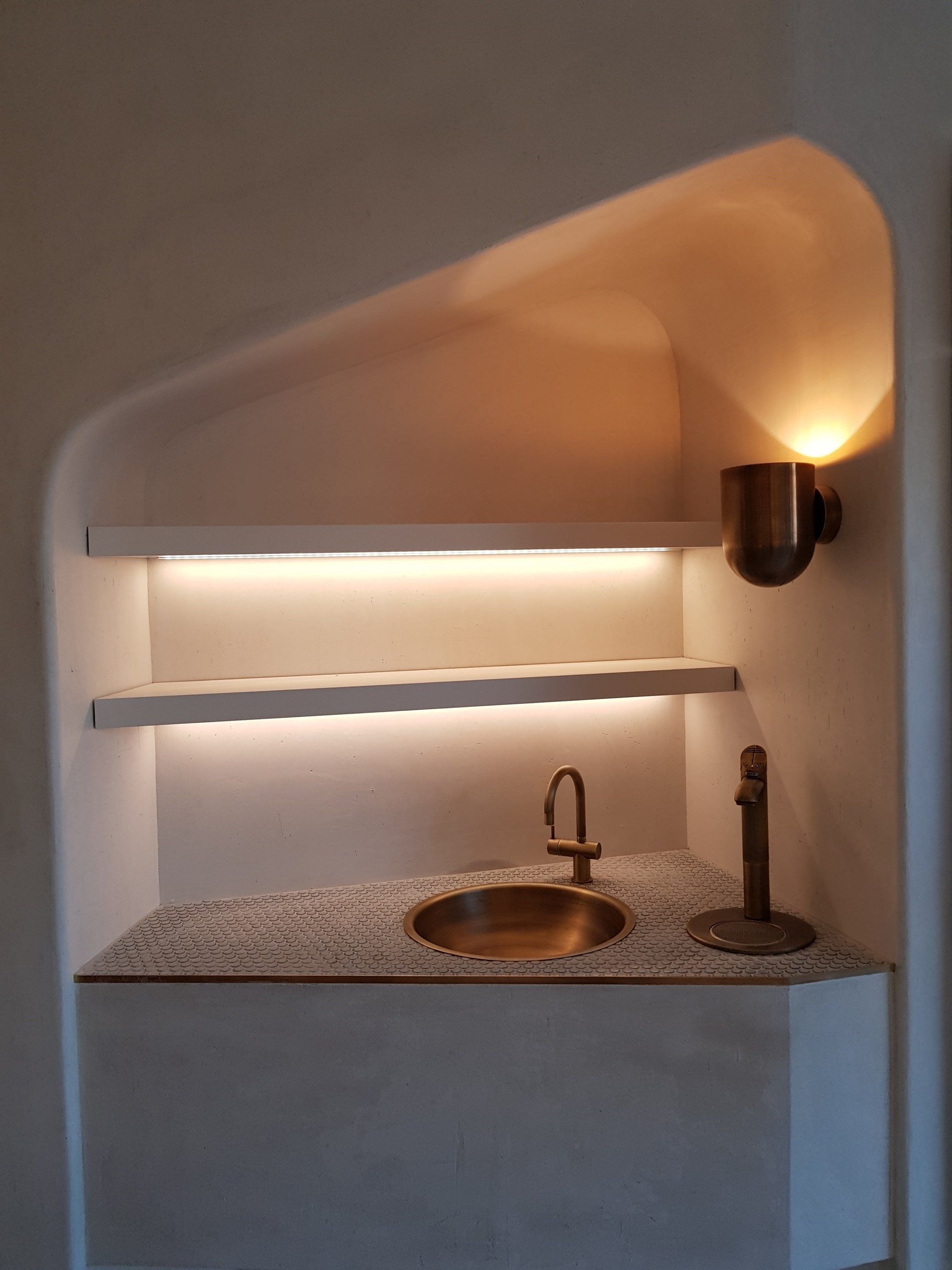 A corner of a room with a sink and shelves