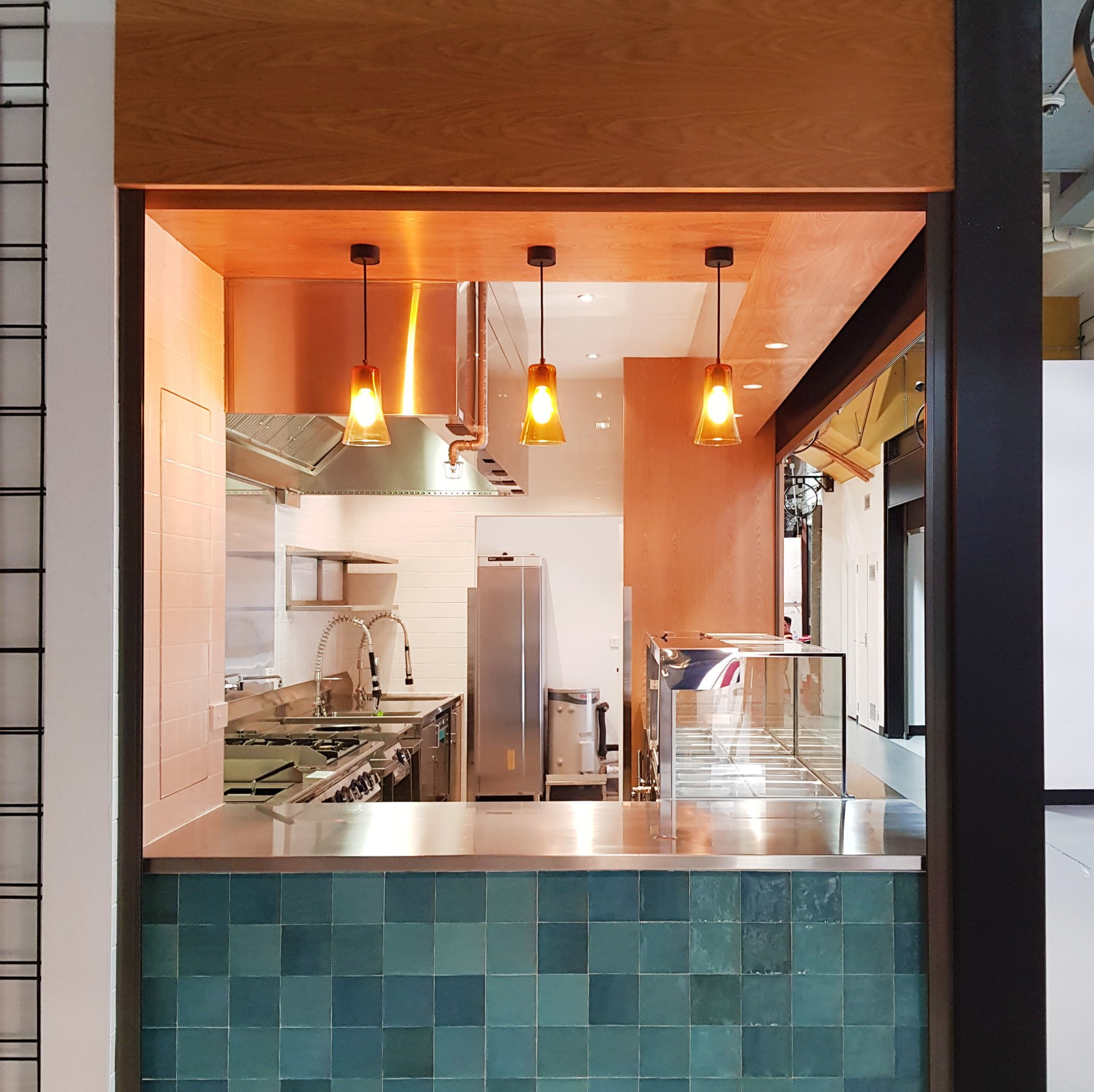 A kitchen with stainless steel appliances and green tiles