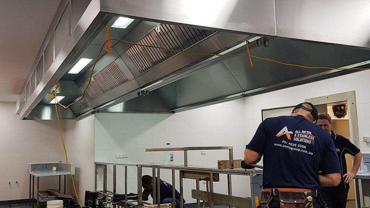 A man in a blue shirt is working in a kitchen.