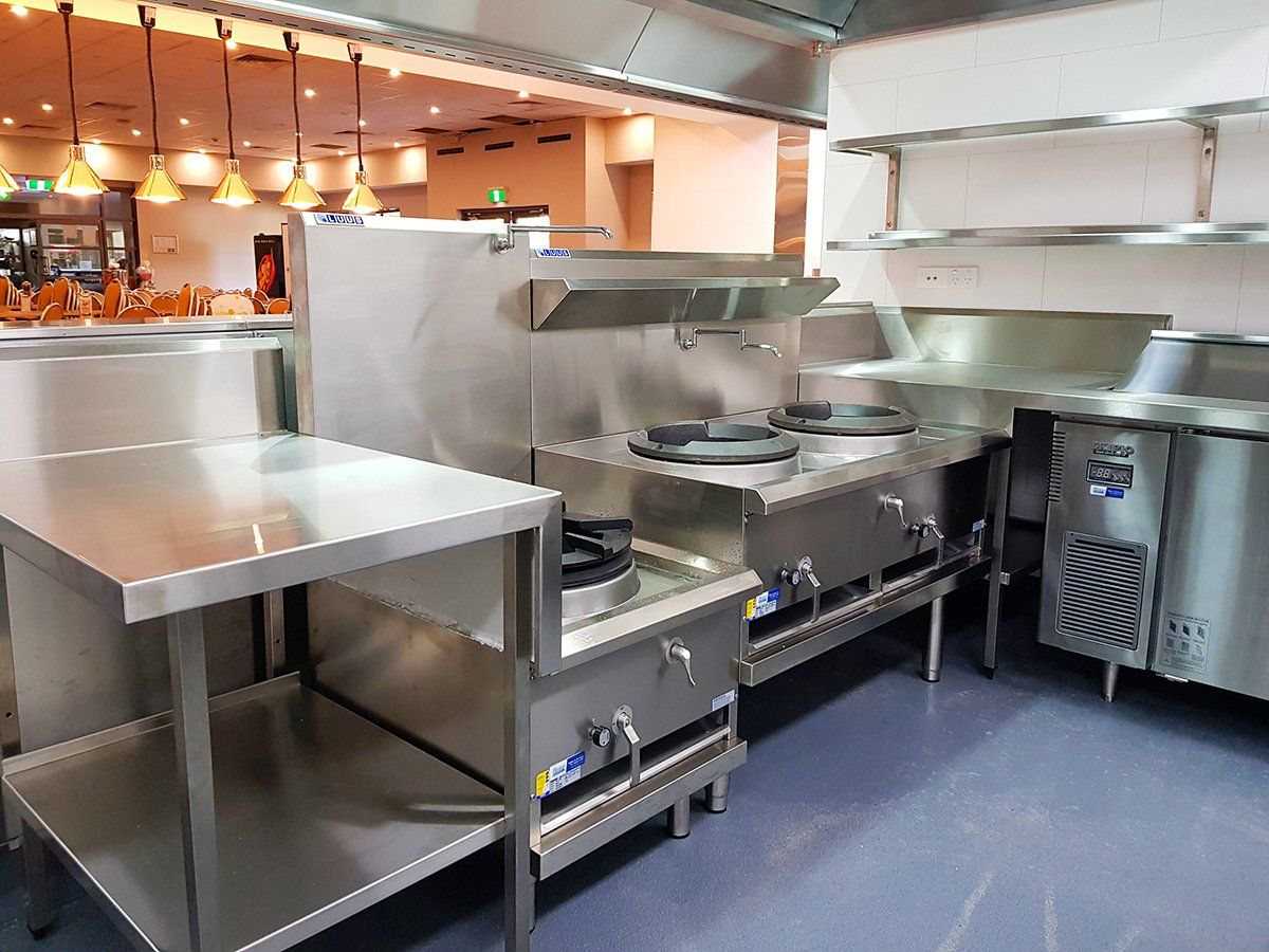 A kitchen with a lot of stainless steel appliances and counters.