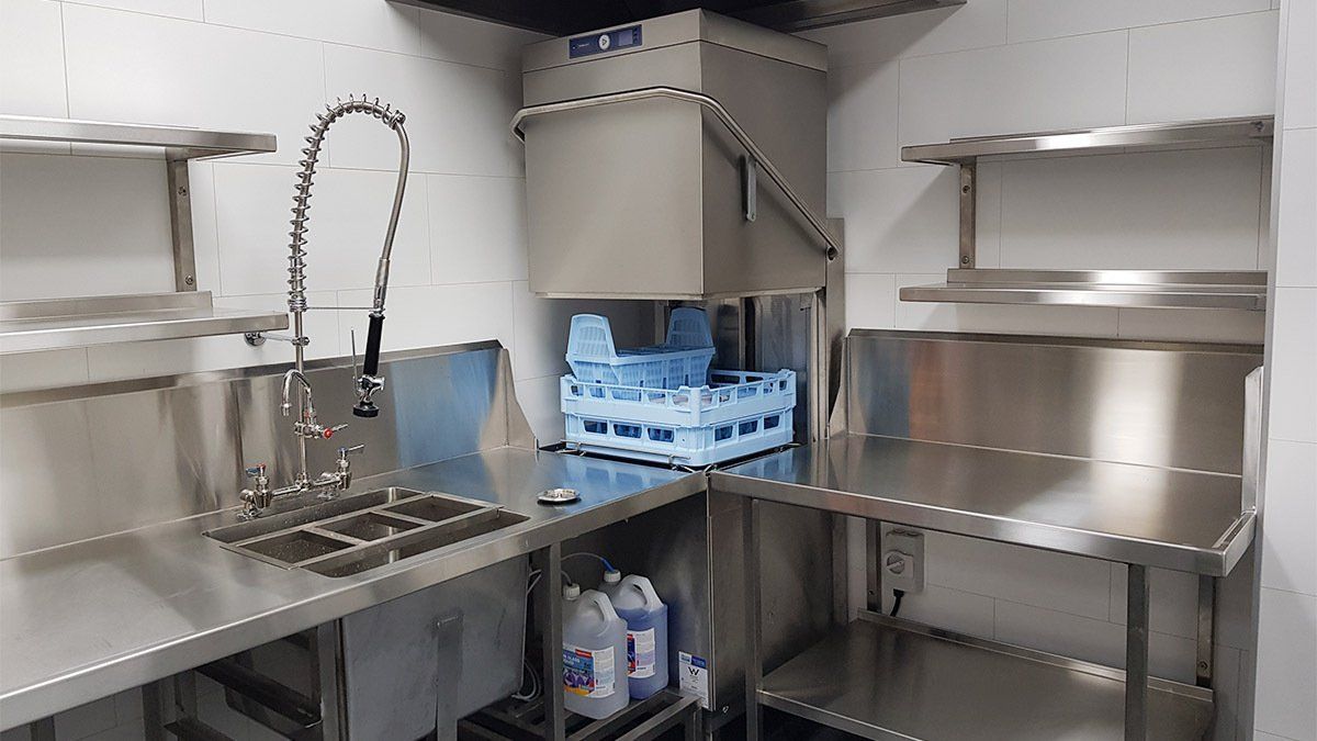 A stainless steel kitchen with a sink , shelves , and a dishwasher.