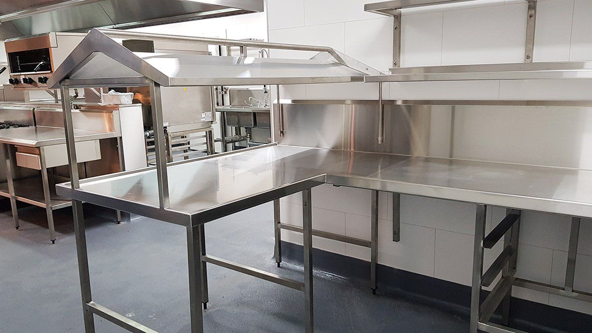 A kitchen with stainless steel tables and shelves.