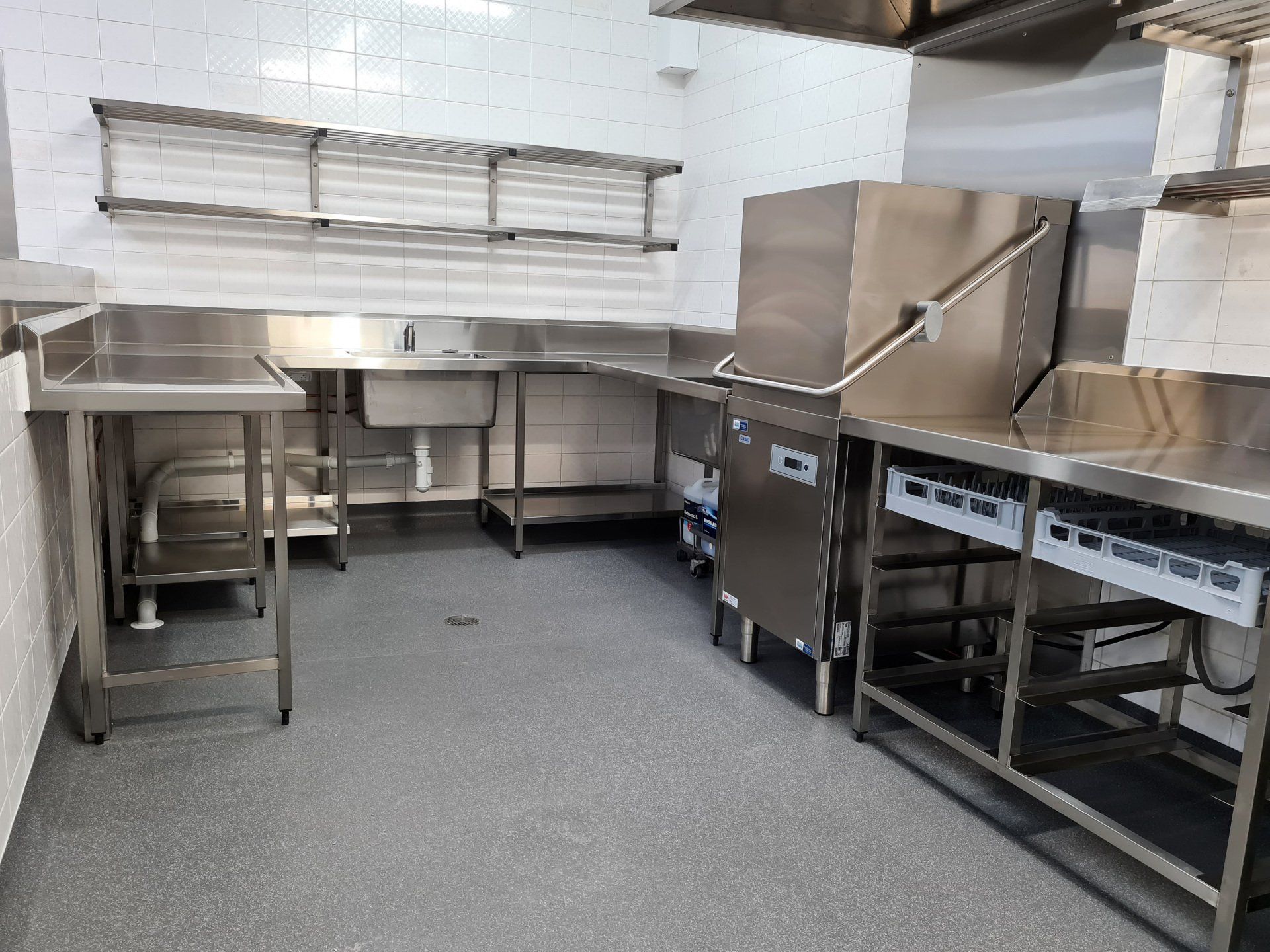 A kitchen with stainless steel counter tops , sinks , and dishwashers.