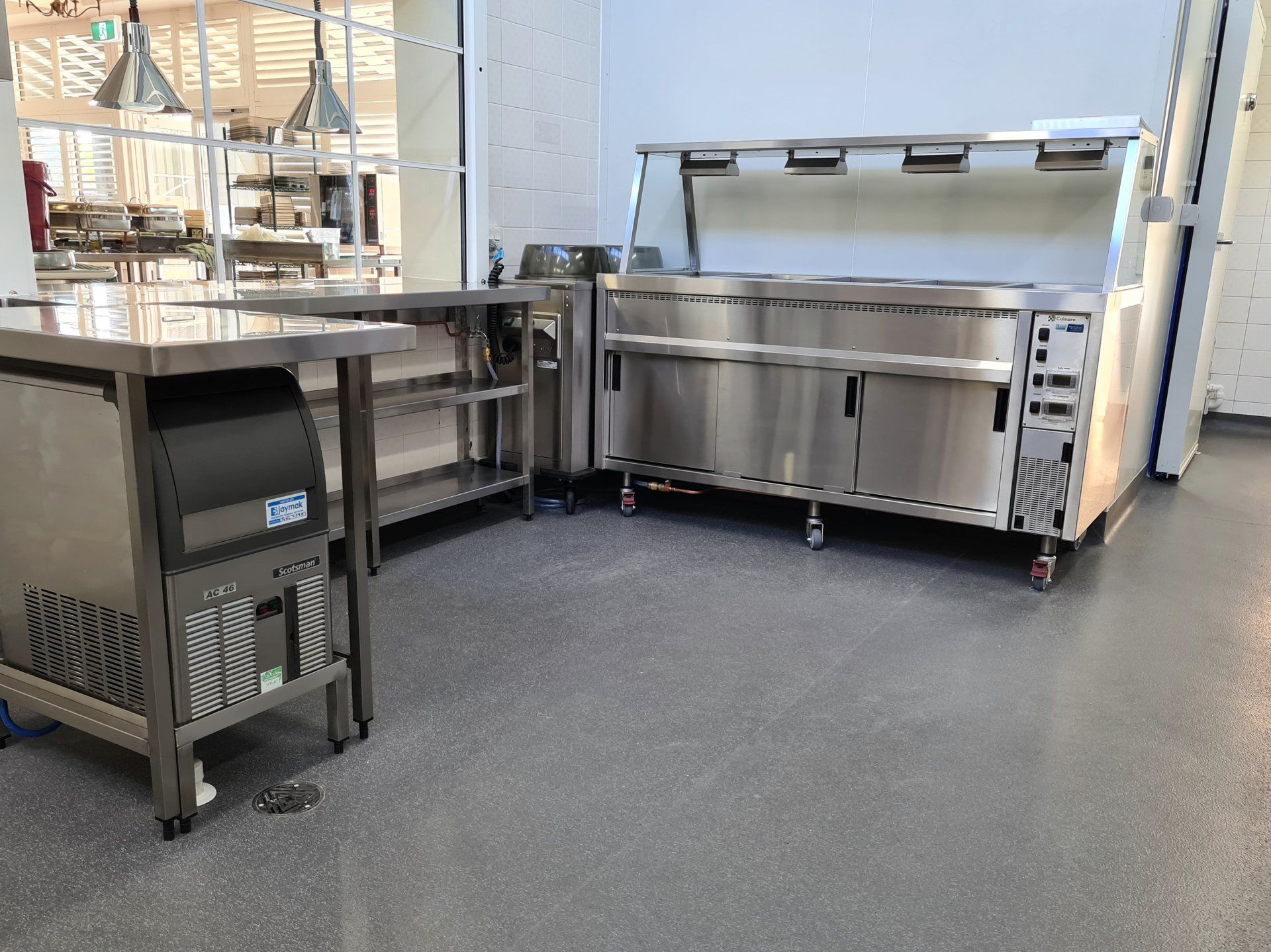 A kitchen with stainless steel appliances and a trash can.