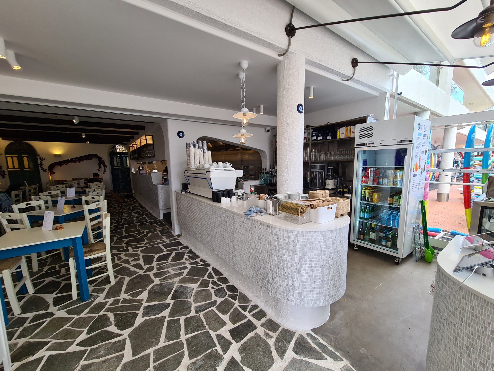 A restaurant with a long counter and tables and chairs