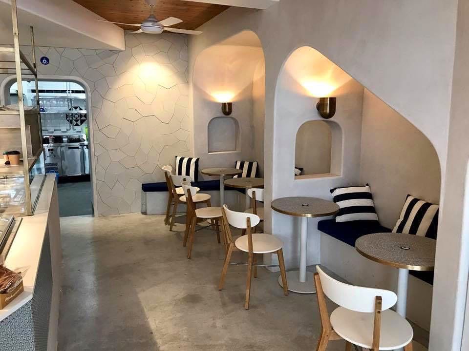 A restaurant with tables and chairs and a staircase leading to the kitchen.