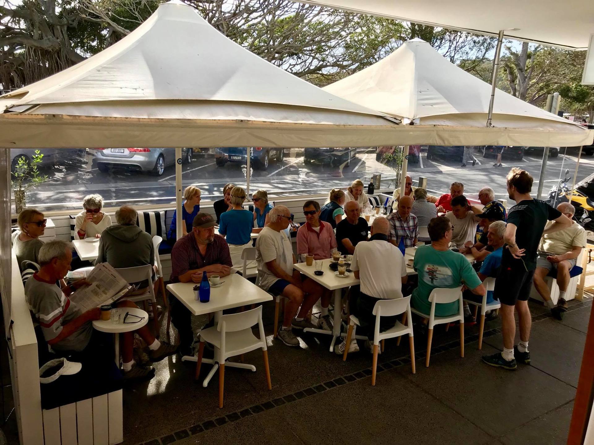 A group of people are sitting at tables under umbrellas.