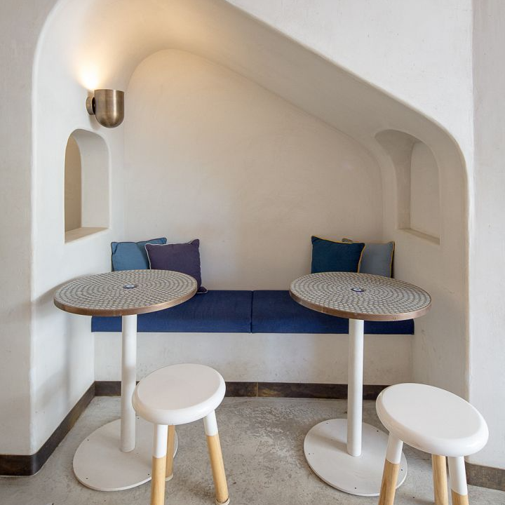 A corner of a room with two tables and two stools