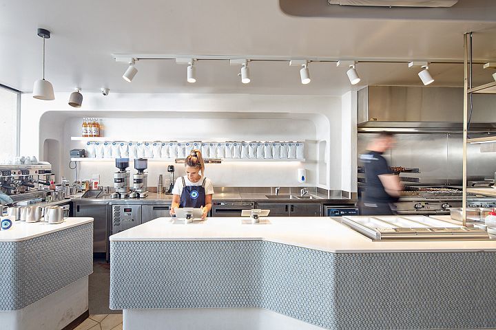 A woman is standing at a counter in a kitchen in a restaurant.