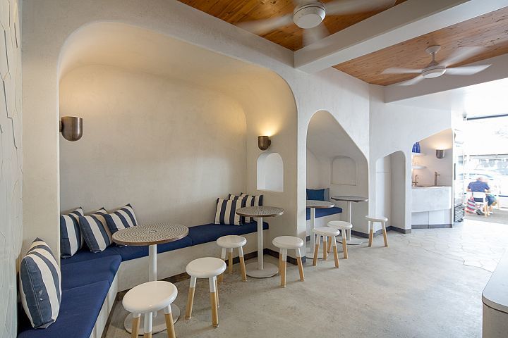 A room with tables and stools and a ceiling fan
