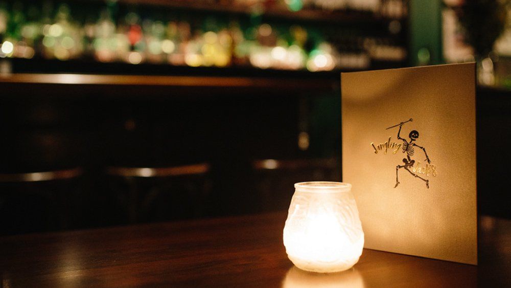 A candle is sitting on a wooden table next to a menu.