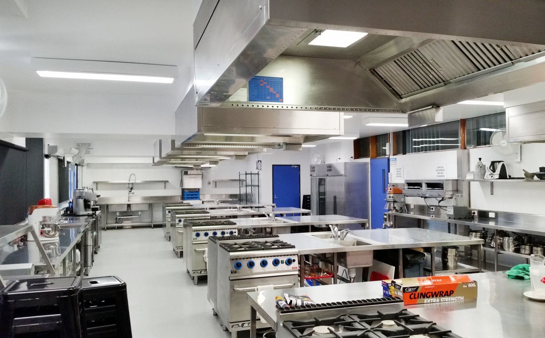 A large commercial kitchen with lots of stainless steel appliances.