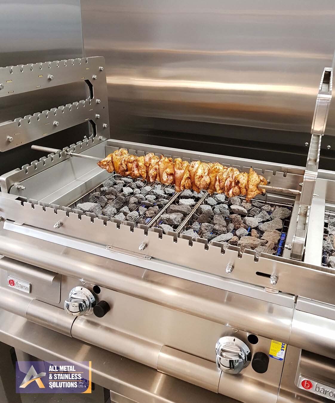 A stainless steel grill with food cooking on it.