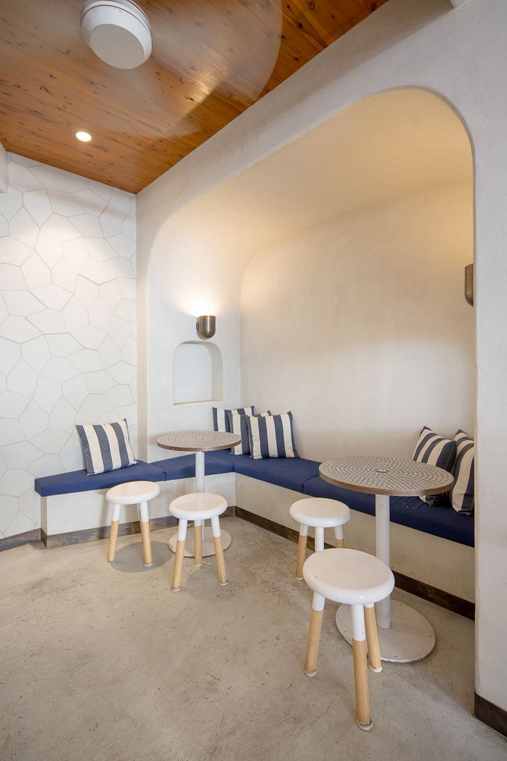 A room with tables and stools and a ceiling fan.