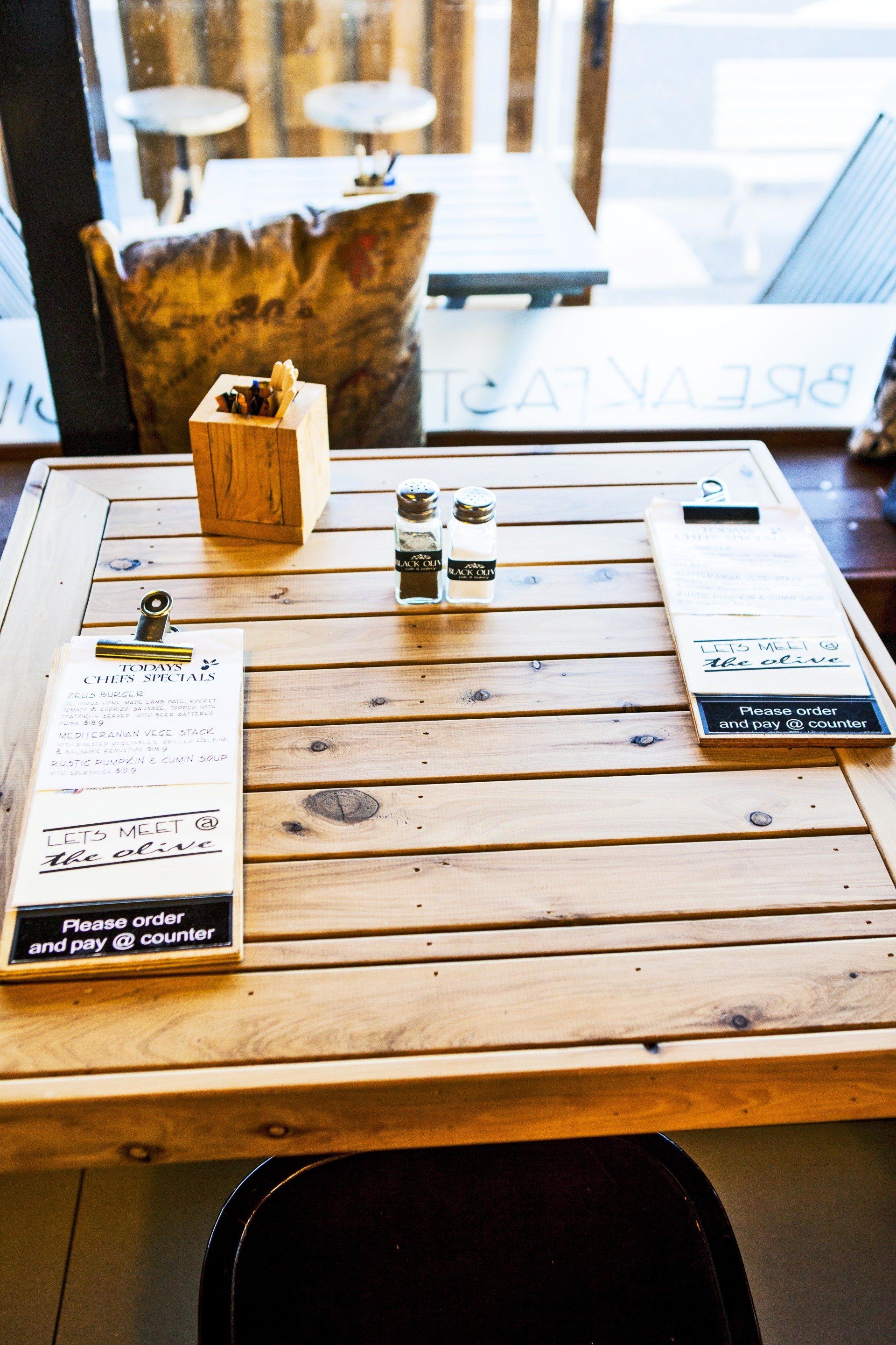 A wooden table with two menus on it in a restaurant.