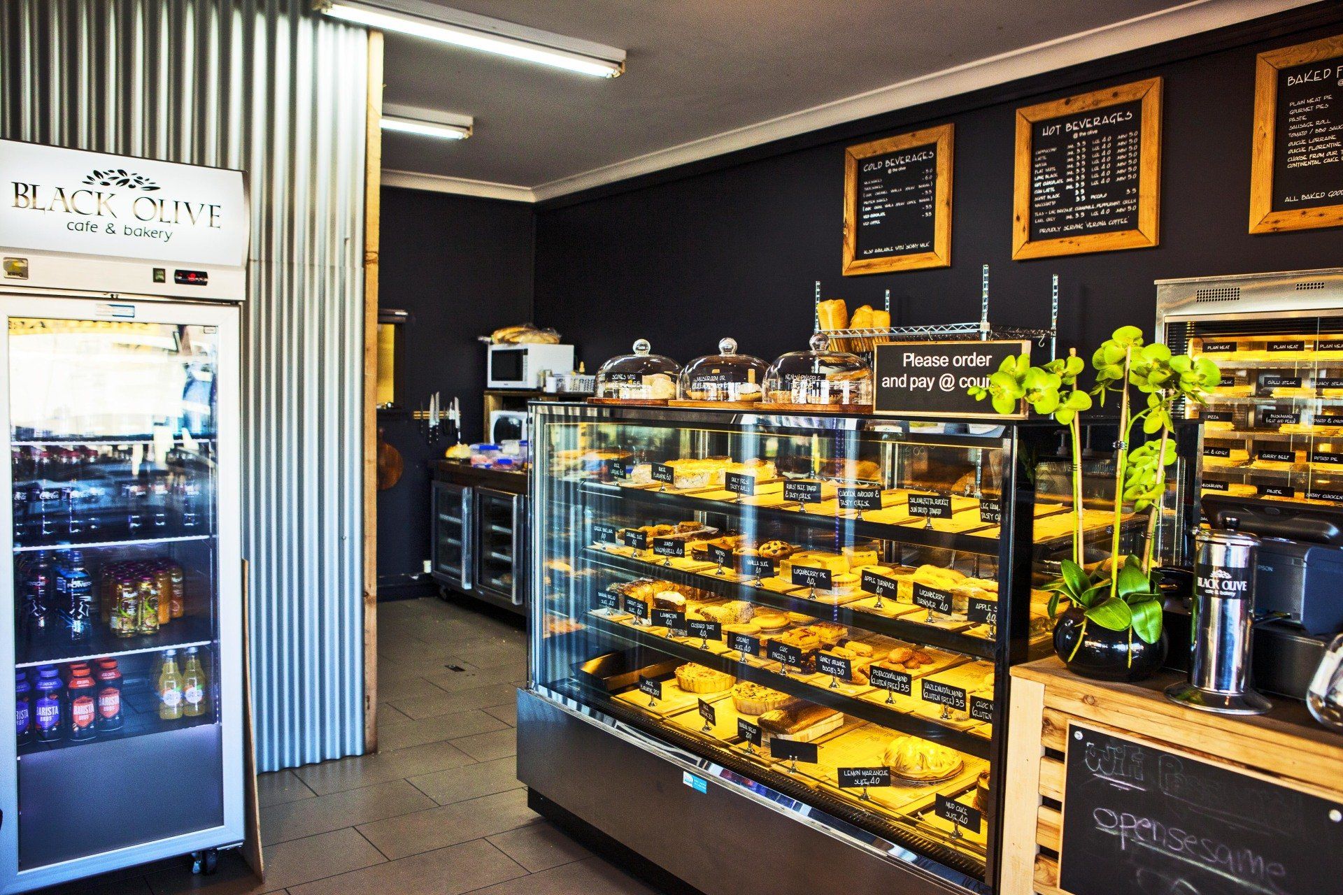 A bakery with a display case filled with lots of food and a refrigerator.