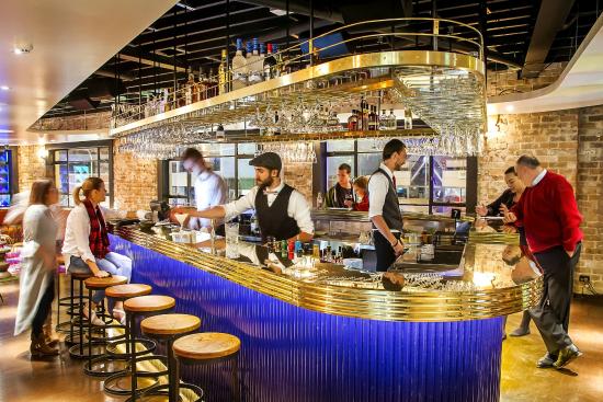 A group of people are standing around a bar in a restaurant.