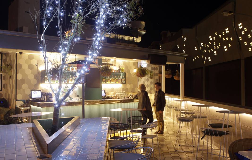 A group of people are standing outside of a restaurant at night.