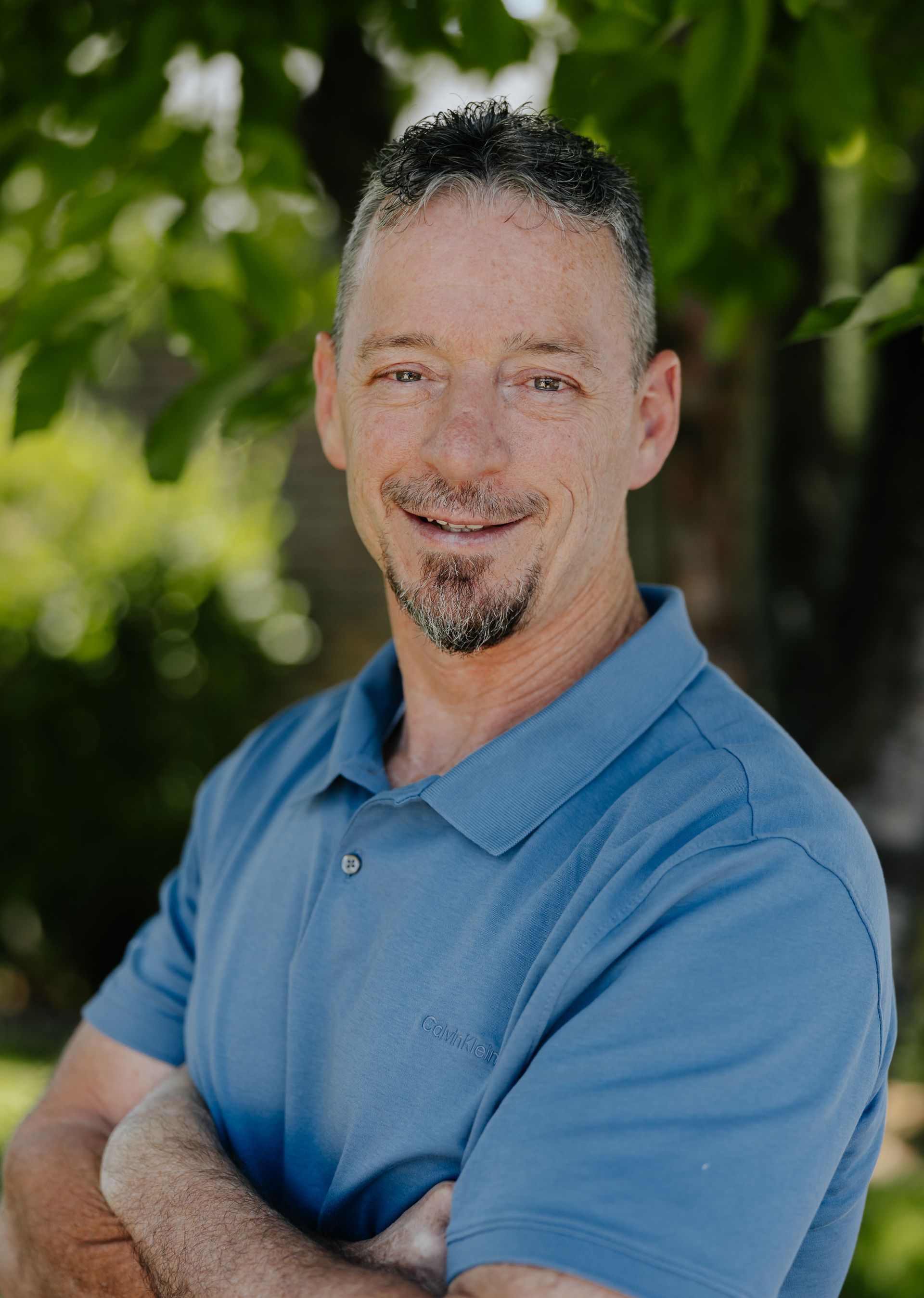 A man with a beard is wearing a white shirt and tie.