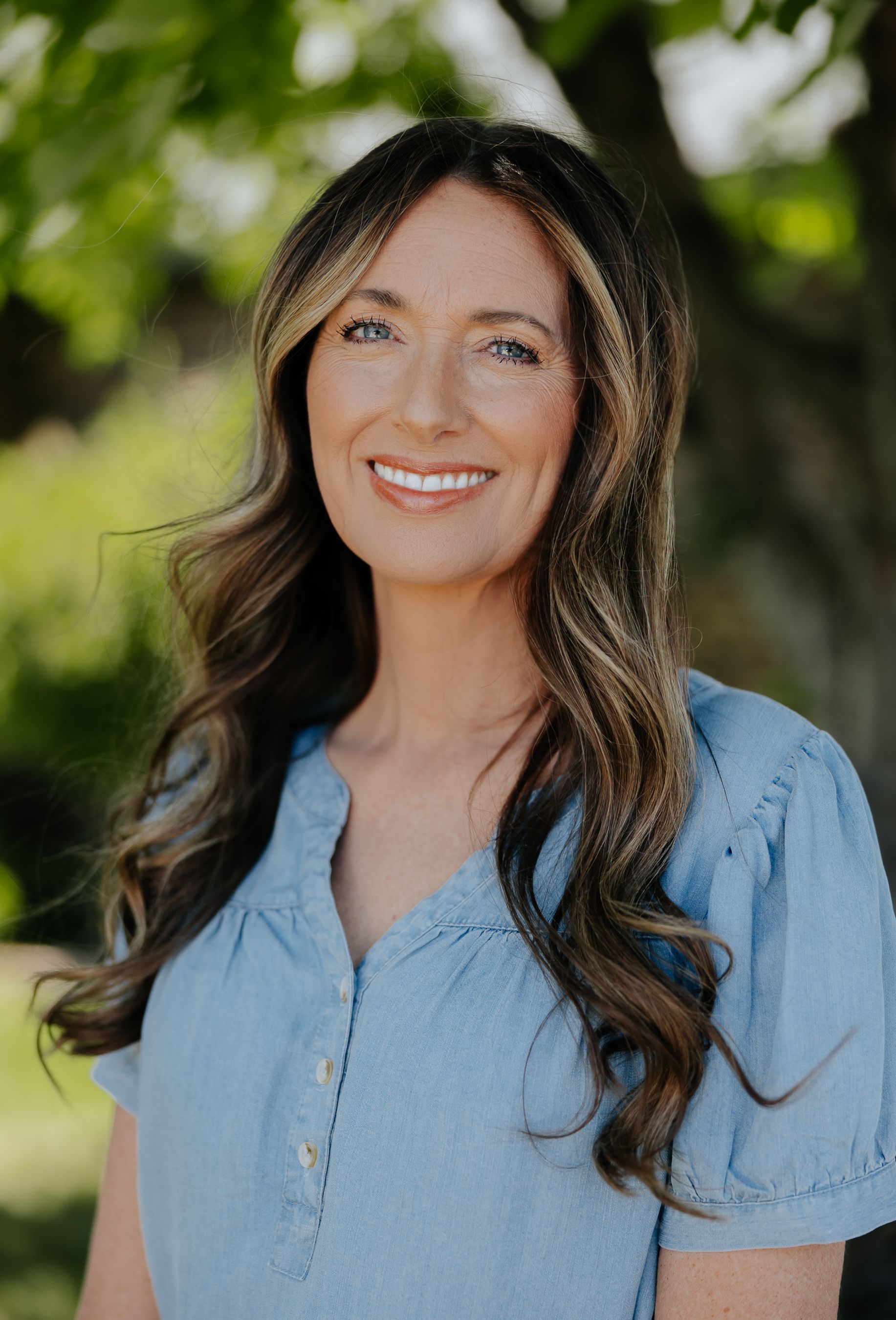 A woman with long blonde hair is smiling for the camera.