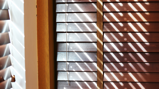 A close up of a window with wooden blinds on it.