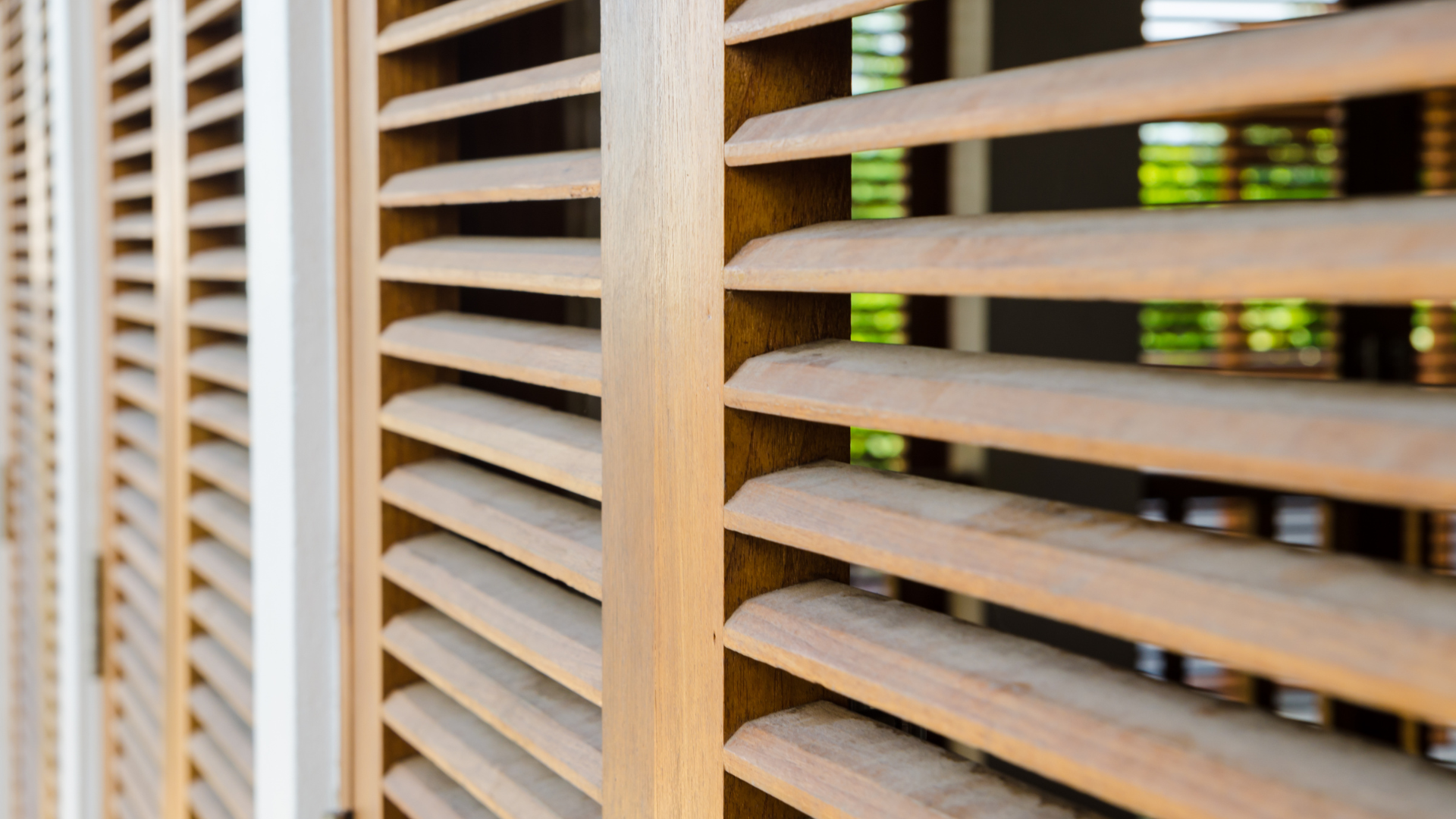 A close up of a row of wooden shutters on a window.