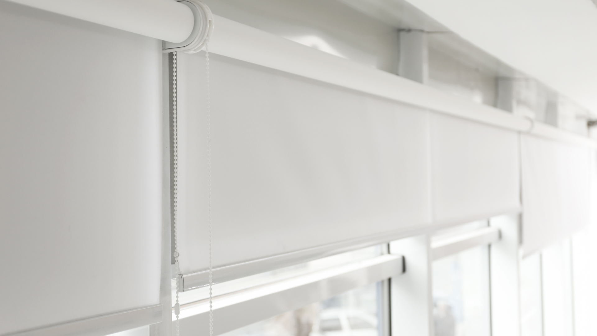 A close up of a white roller blind on a window.